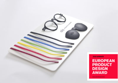 Lunettes QLIP imprimées en 3D en pièces détachées de couleurs différentes sur un présentoir avec le prix European Product Design Award