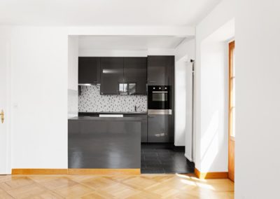 Vue de la nouvelle cuisine d'un appartement rénové dans le cadre de notre prestation d'architecture d'intérieur. Avec ablation d'un mur de séparation et ilot de cuisine qui sert de séparation fonctionnelle.